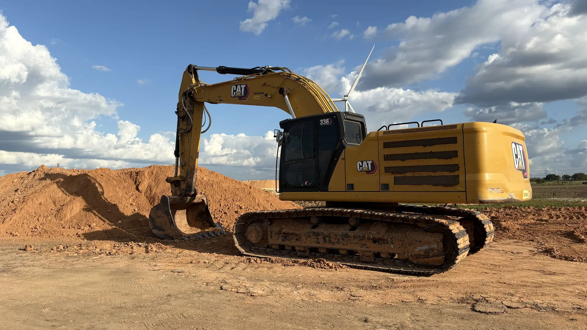 CAT excavator working a select fill stockpile under a blue sky