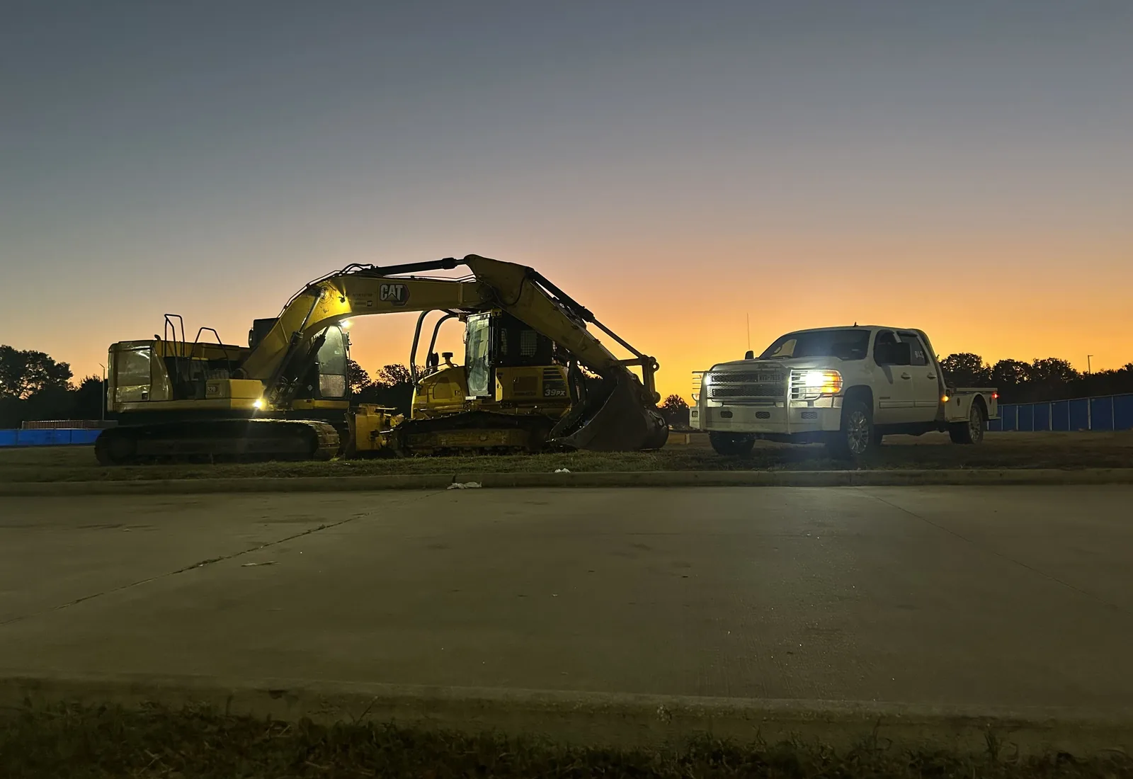 RLS crew truck parked beside an excavator bucket at sunset