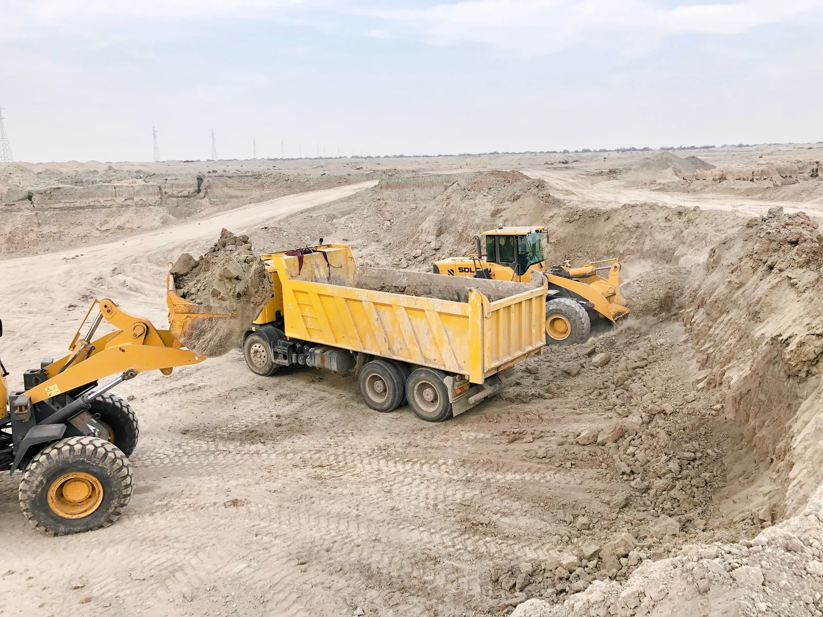 Wheel loaders filling a tandem dump truck at a sand pit