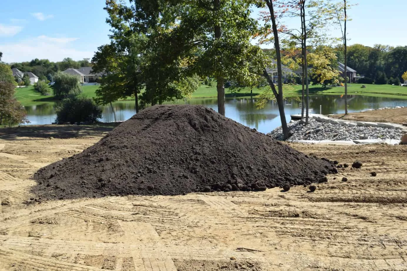 Dark topsoil pile stockpiled on a sandy work site